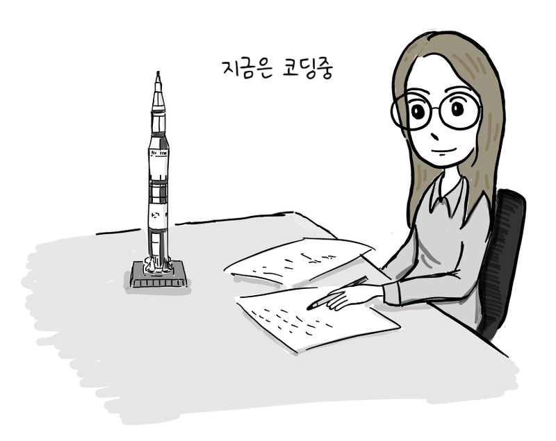 프로그래머가 모형 로켓을 옆에 두고 책상에서 종이에 코드를 쓴다.