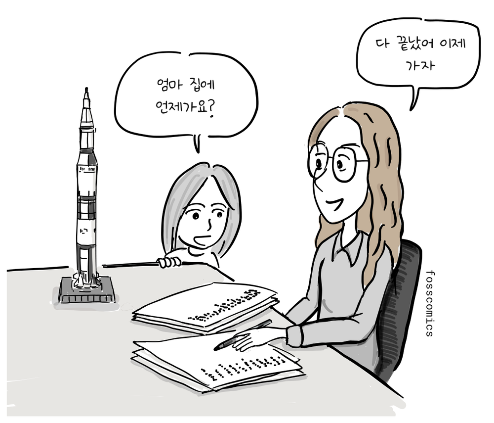 마거릿 해밀턴이 책상에서 일하고, 딸은 새턴 V 로켓 모형 옆에서 기다린다.