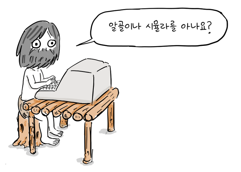 수염을 기른 프로그래머가 통나무 탁자 위의 컴퓨터로 작업한다.