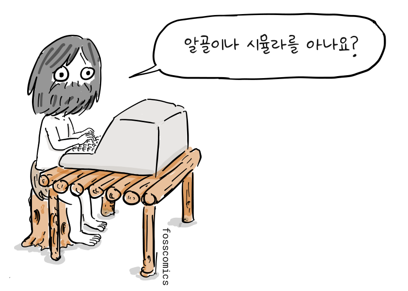 수염을 기른 프로그래머가 통나무 탁자 위의 컴퓨터로 작업한다.