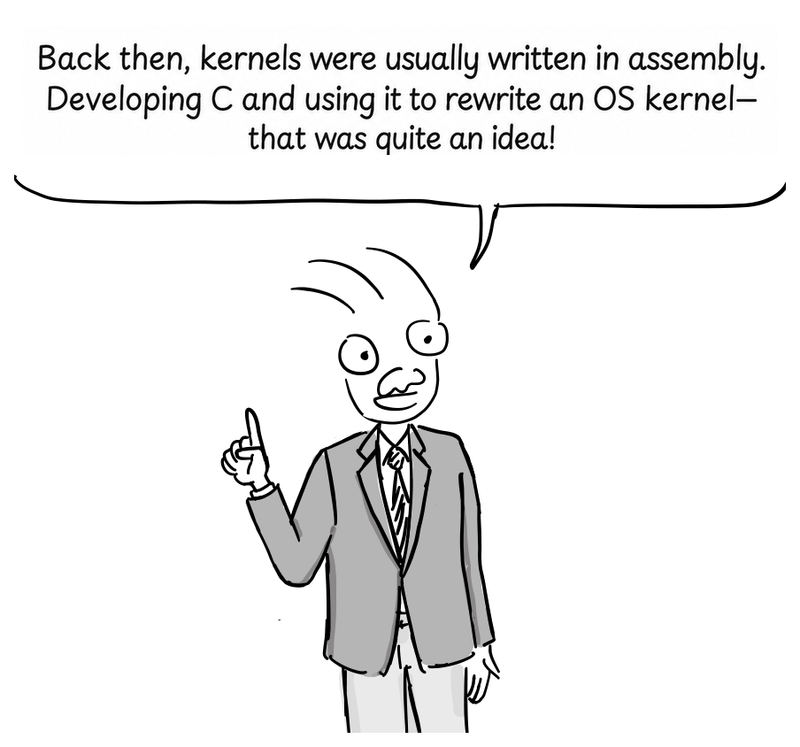 A presenter in a suit raises one finger while discussing the move from assembly language to C.